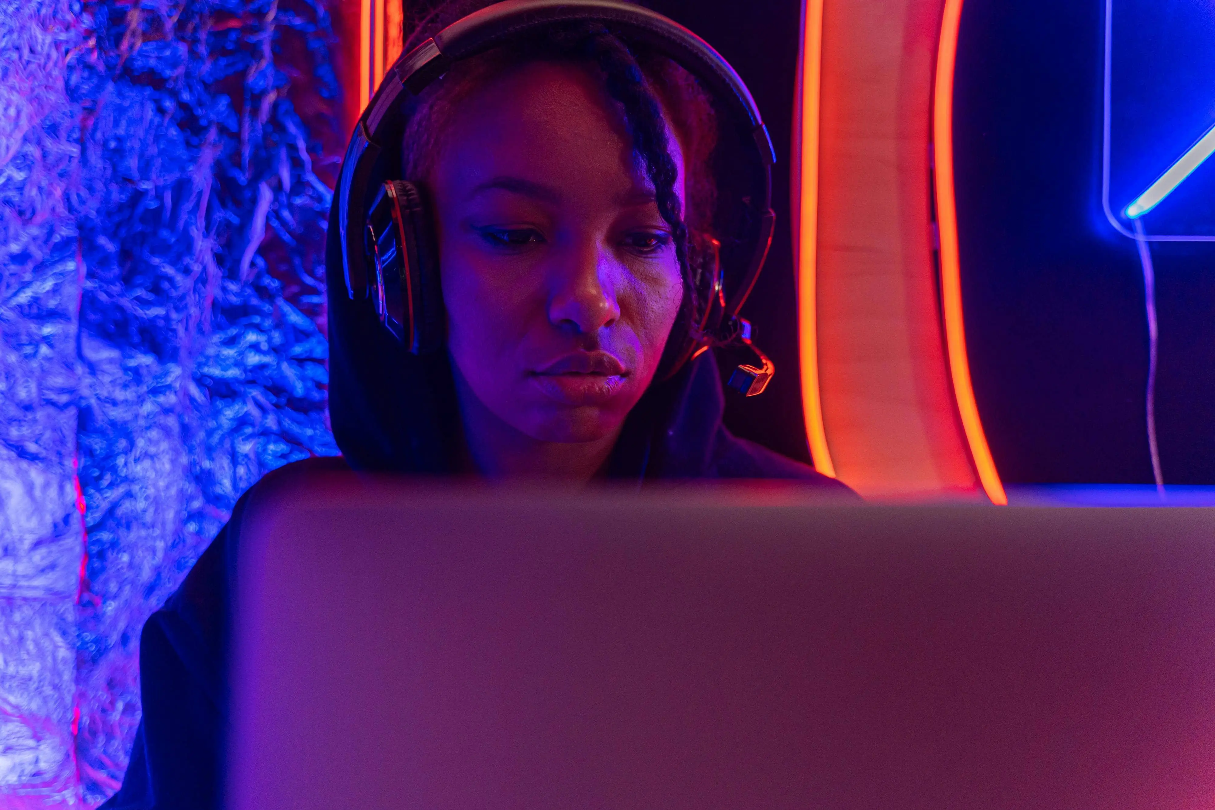 A female gamer with headphones behind a computer screen.